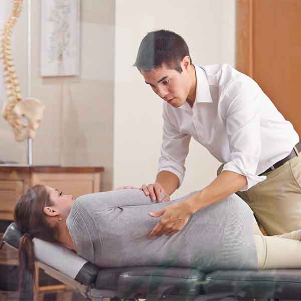 A chiropractor adjusting a young woman's spine